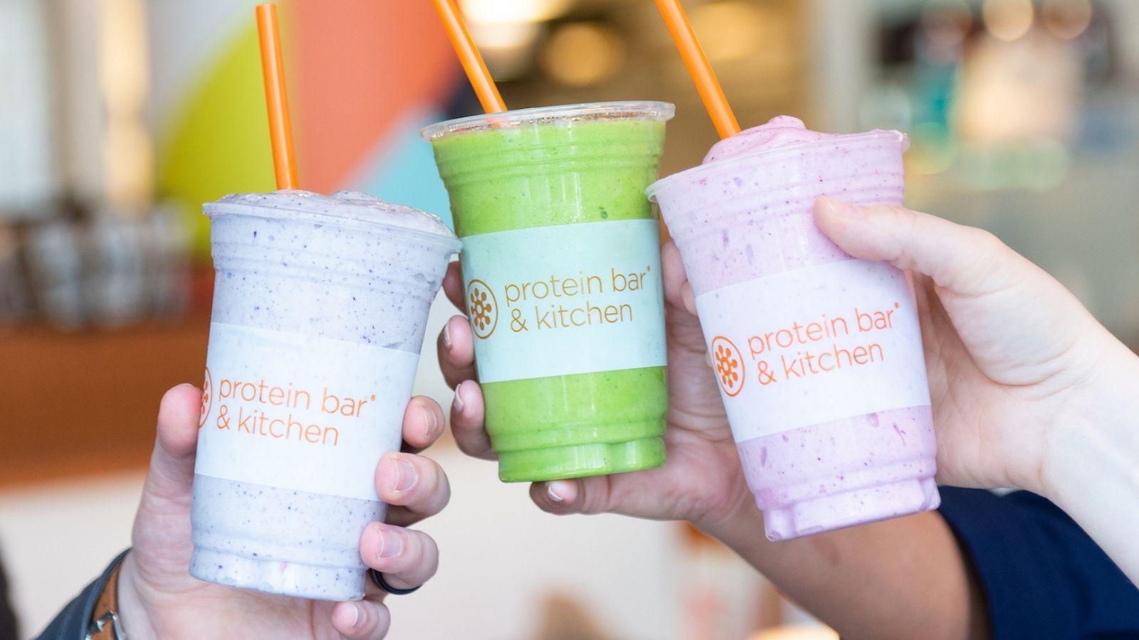 Three Protein Bar & Kitchen smoothies held up side by side